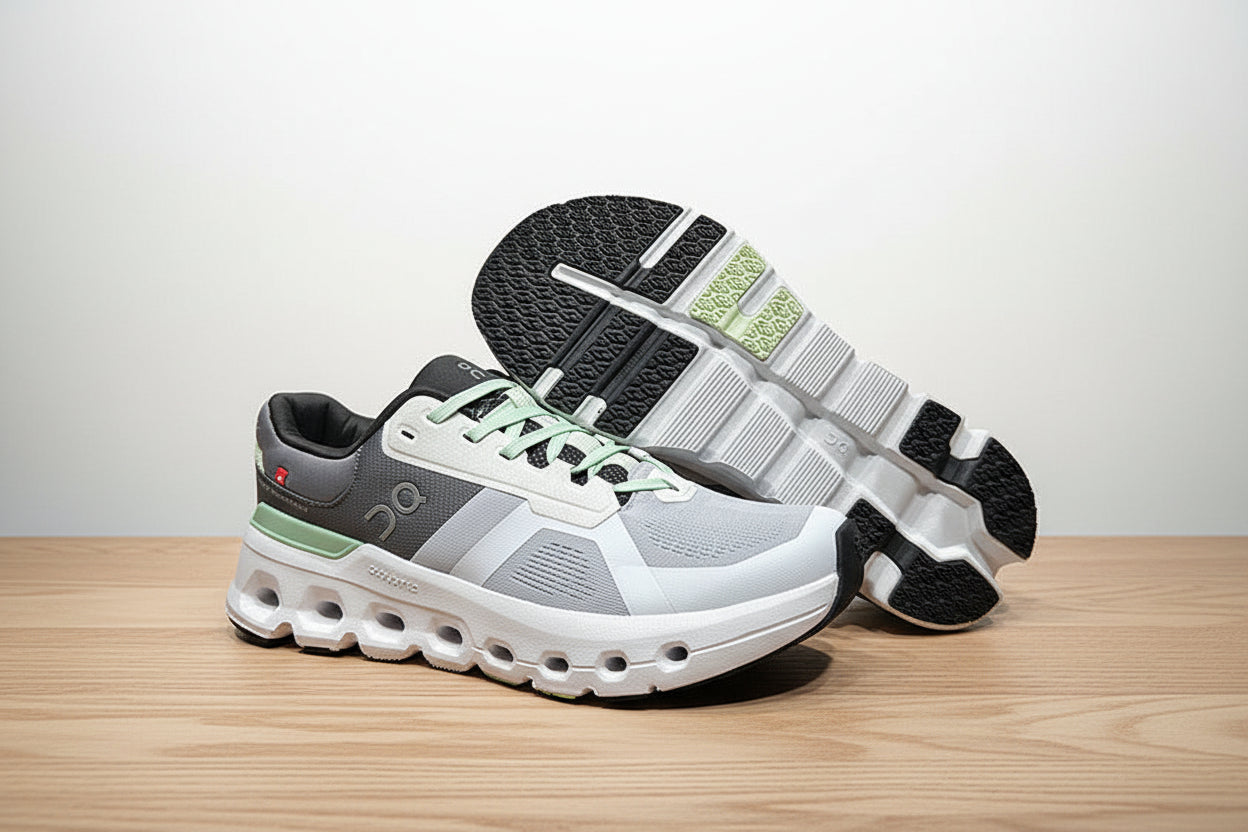 Gray and white sneakers with green accents on a light gray surface.