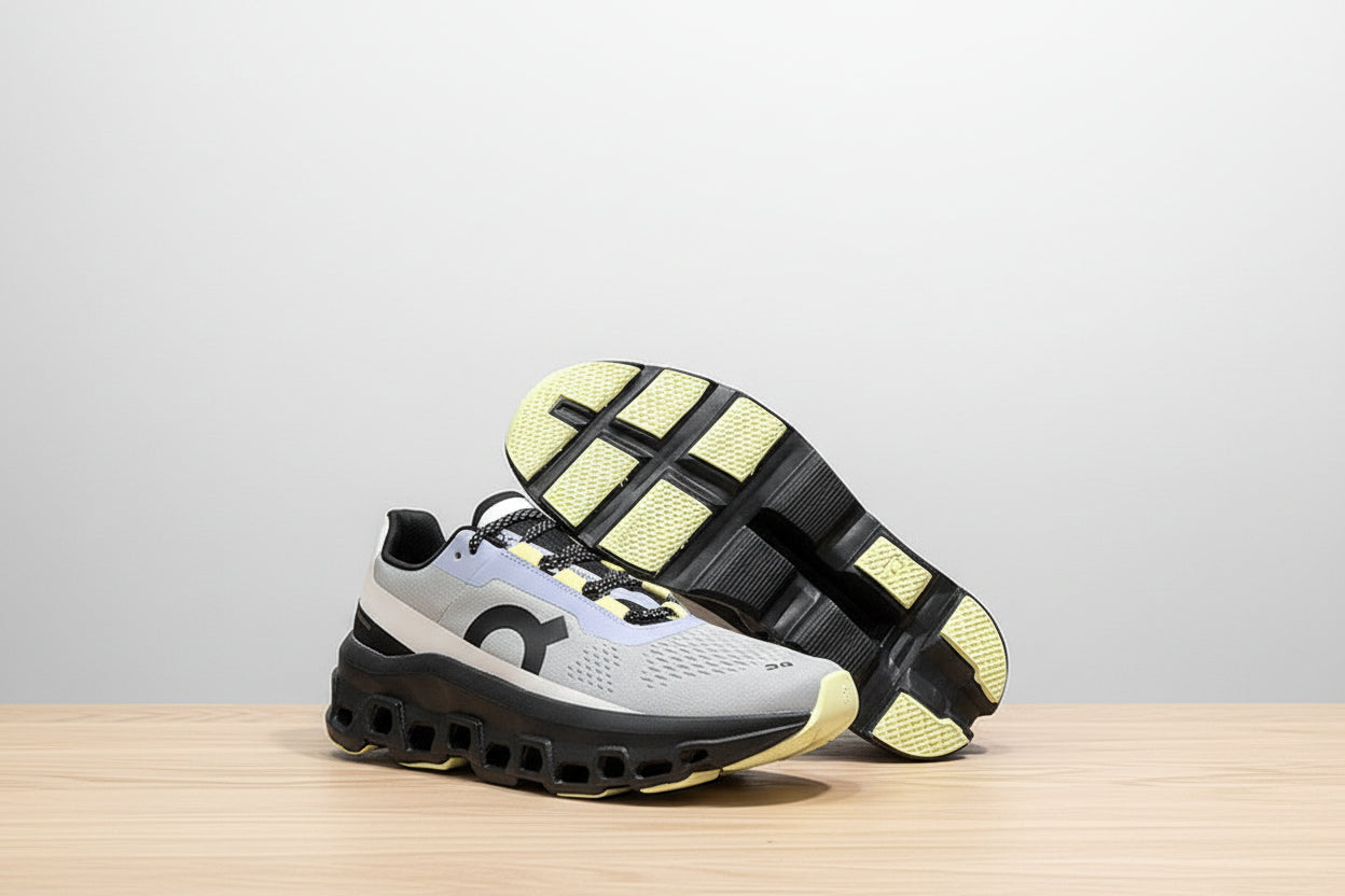 Gray and black sneaker with yellow sole on a white surface