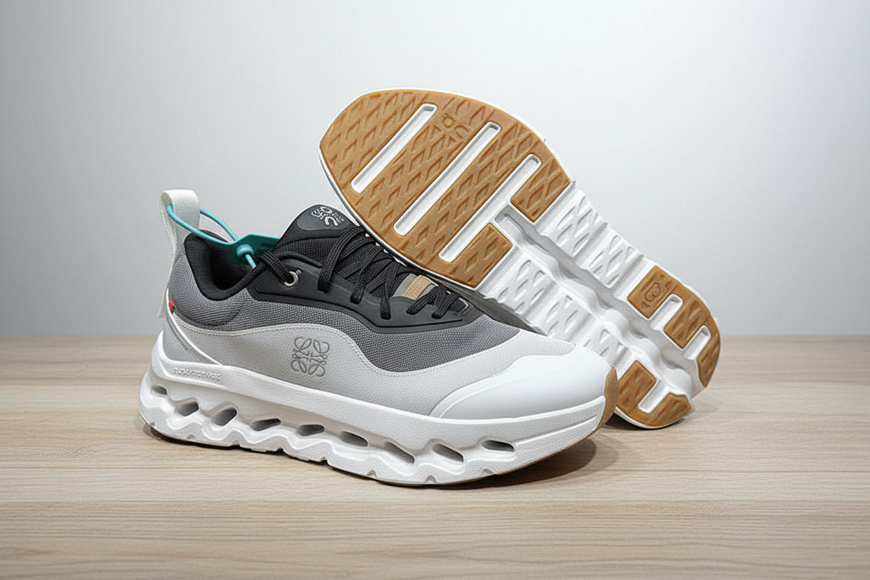 Gray and white sneakers with a brown sole on a light gray surface.