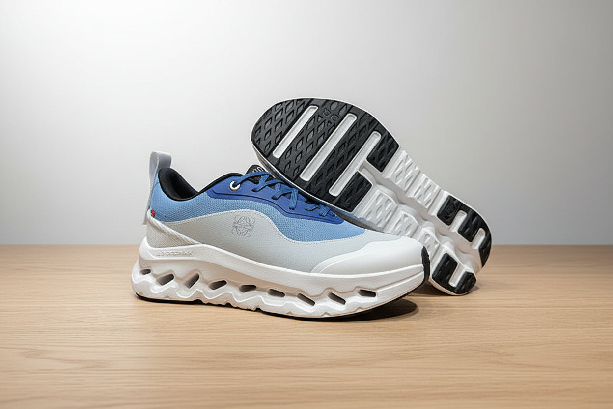 Blue and white sneaker with black sole on a gray surface