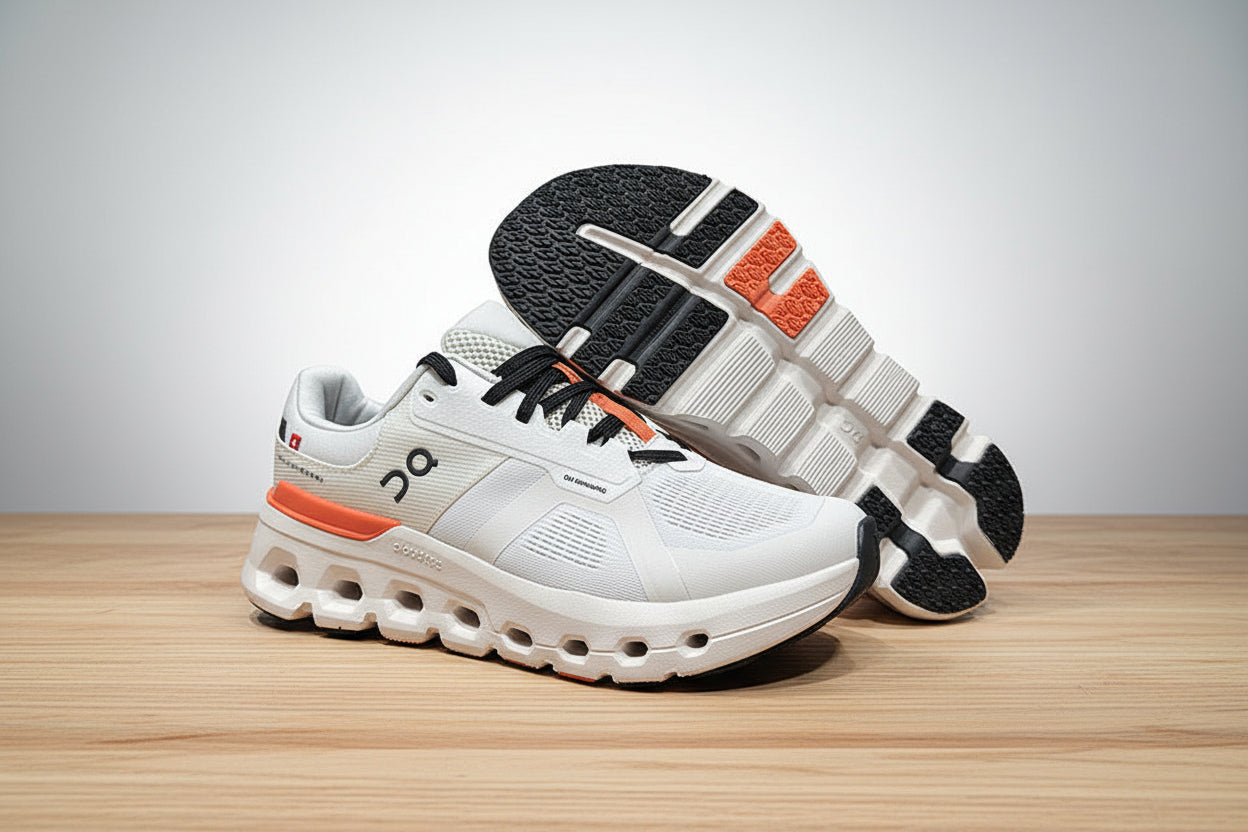 White athletic shoes with black and orange accents on a light gray surface.
